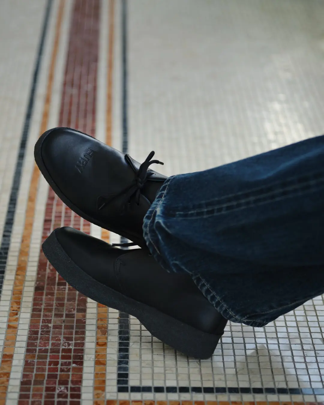 Black FURY leather lace-up shoes worn with dark blue jeans on a multicolored mosaic tile floor.