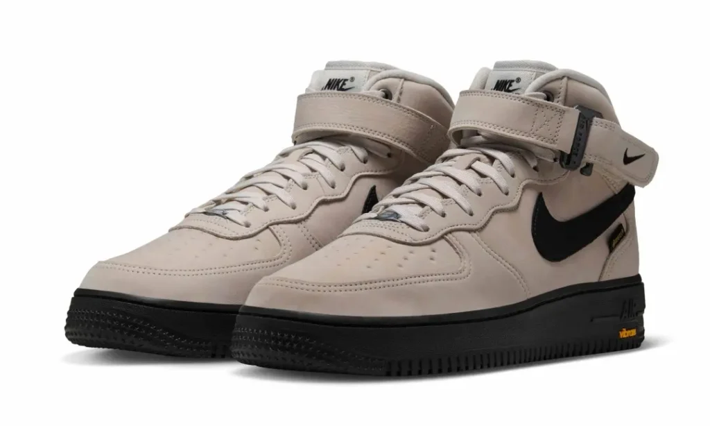 Pair of light beige Nike Air Force 1 Mid shoe with black Swoosh, ankle strap, GORE-TEX construction and black Vibram sole