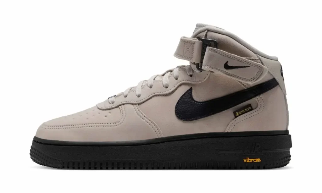 Side profile of a light beige Nike Air Force 1 Mid with black Swoosh, GORE-TEX label and black Vibram outsole