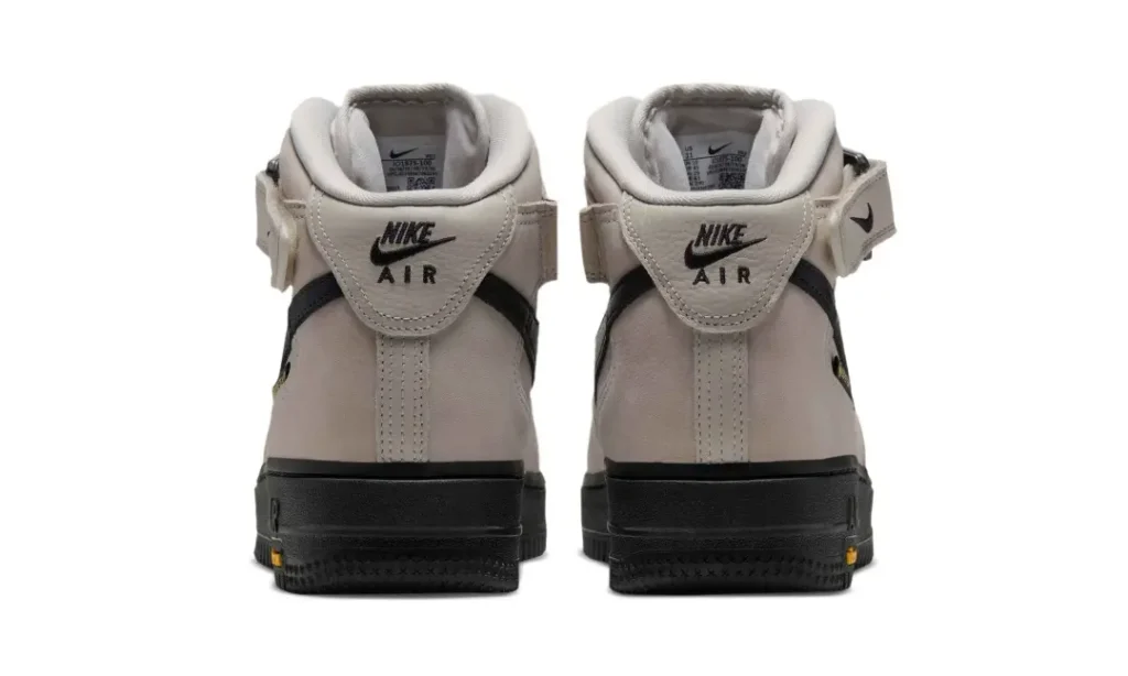 Rear view of a pair of beige Nike Air Force 1 Mid shoe show Nike Air heel brand and black sole