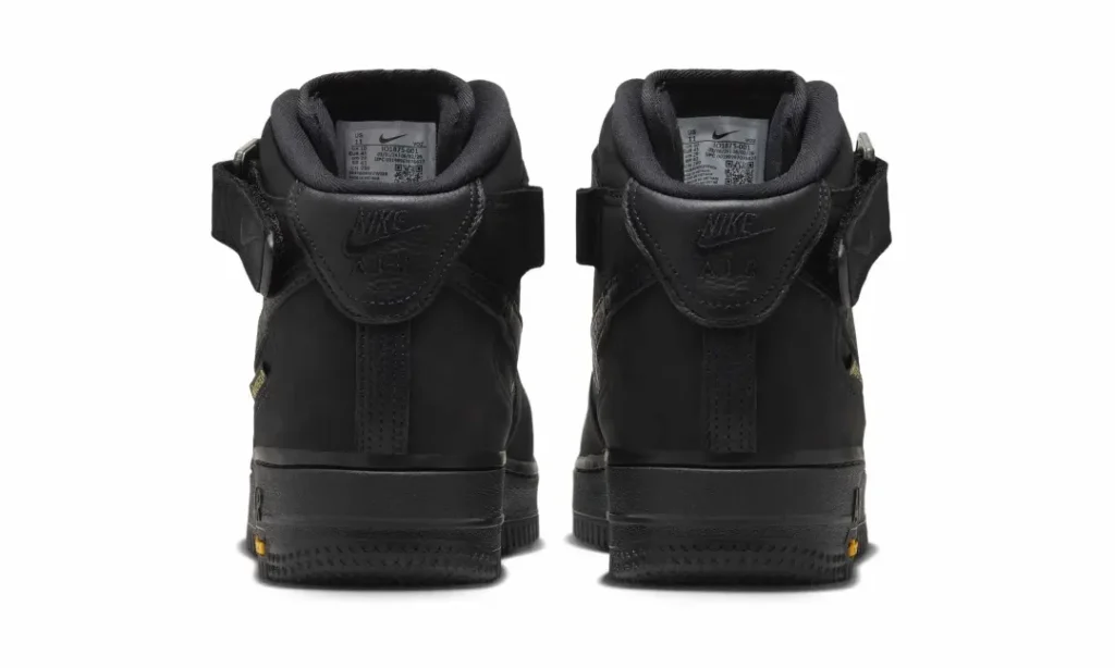 Rear view of a pair of black Nike Air Force 1 Mid shoe show ankle strap, heel panels and black midsole
