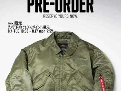 Alpha Industries olive green flight jacket with utility pocket, tonal patche, front zip closure, and red “Remove Before Flight” sleeve tag, shown in a mix.tokyo pre-order promotion