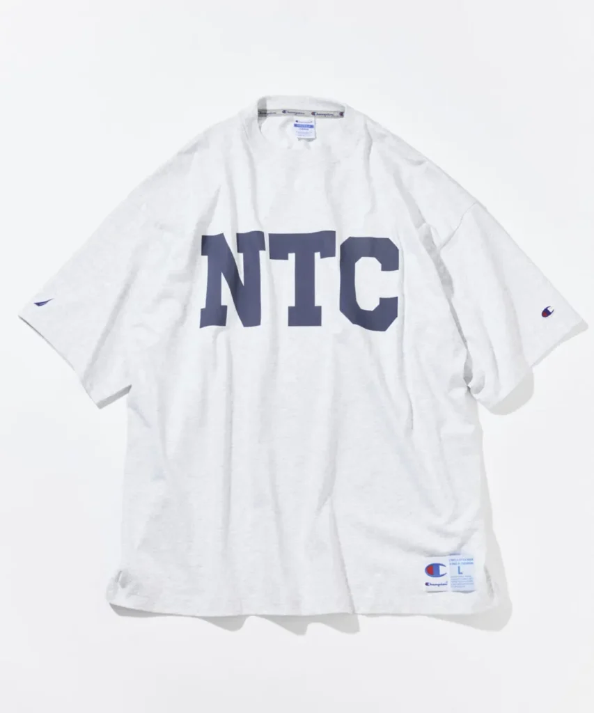 Light gray Champion x Nautica oversized Tee feature a large navy NTC graphic across the chest and collide hem label