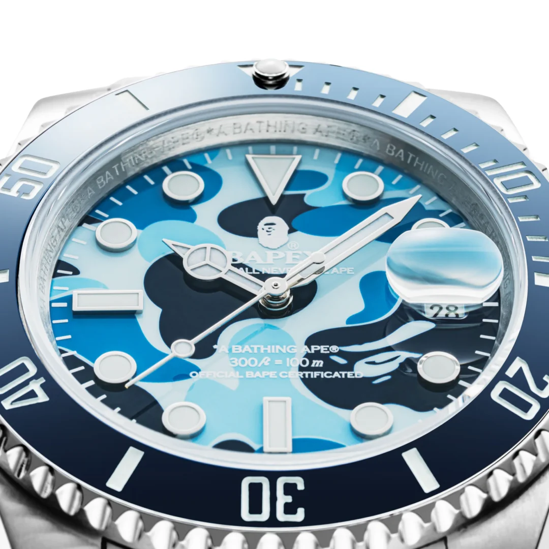 Close-up of a blue BAPEX watch featuring a blue camouflage dial, luminous markers, blue bezel, and date window.