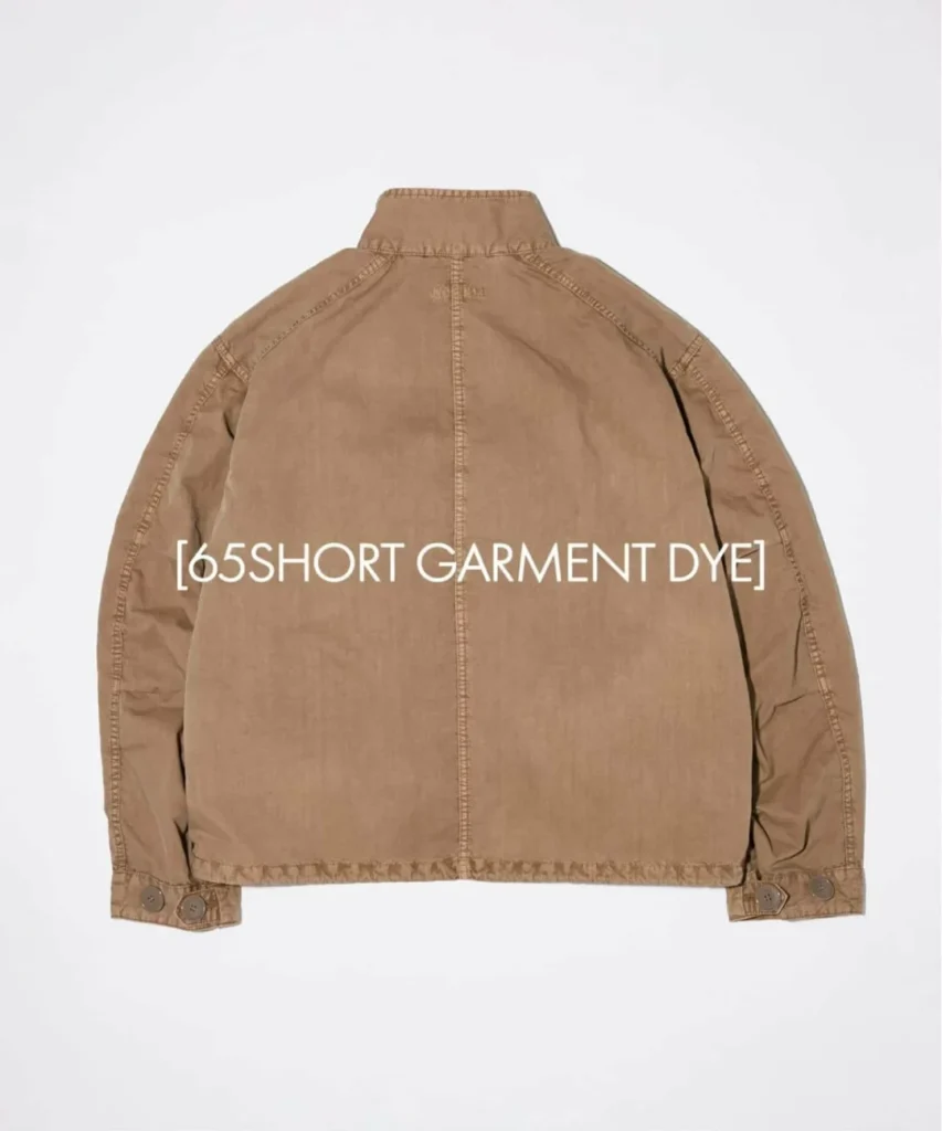 Rear view of the khaki garment-dyed jacket showing clean seam construction, stand collar, and button-adjustable sleeve tab