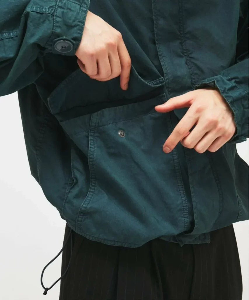 Close-up of the teal jacket reveal the interior pocket, snap closure, garment-dyed finish, and adjust drawcord hem