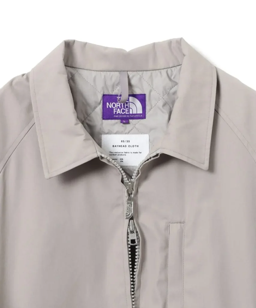 Close-up of the jacket's collar showing the purple The North Face Purple Label tag, two-way zipper, and vertical chest pocket detail
