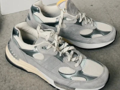 Grey New Balance 992 shoe with mesh, silver accents, white lace, and a cream midsole on concrete