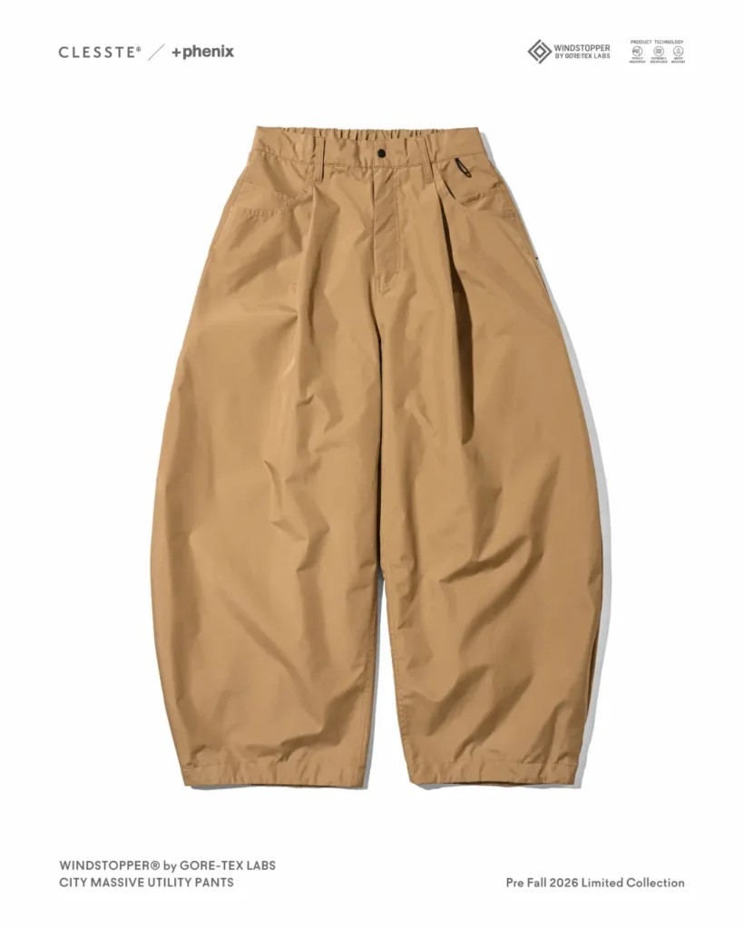 Tan/khaki balloon-fit utility pants with elasticated waist, front pleats, zip coin pocket, and curved barrel-leg silhouette, laid flat on white background