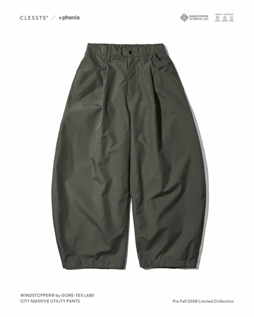 Olive/dark green balloon-fit utility pants with elasticated waist, front pleats, zip coin pocket, and curved barrel-leg silhouette, laid flat on white background