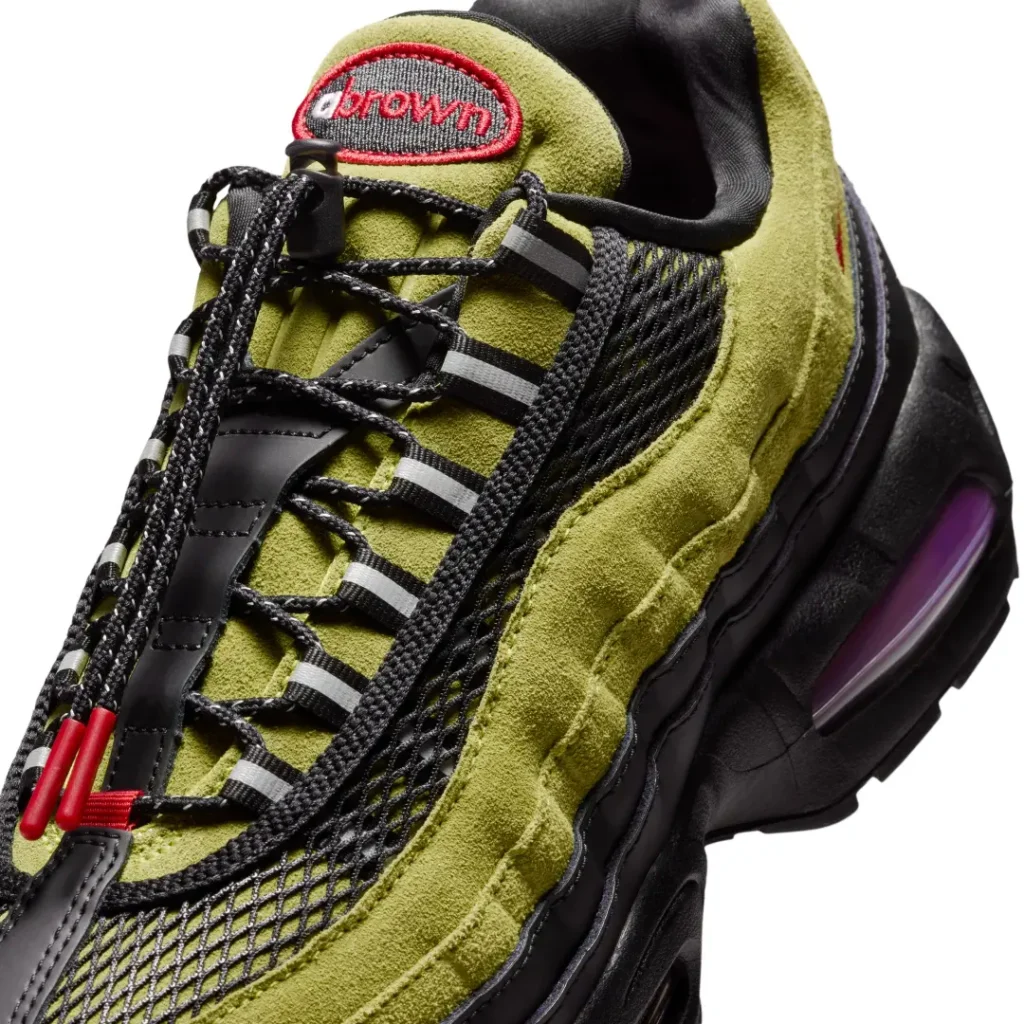 Close-up of the A Ma Maniére x Nike Air Max 95 highlight olive suede, black mesh, reflective lace loop, rope laces, and red accent