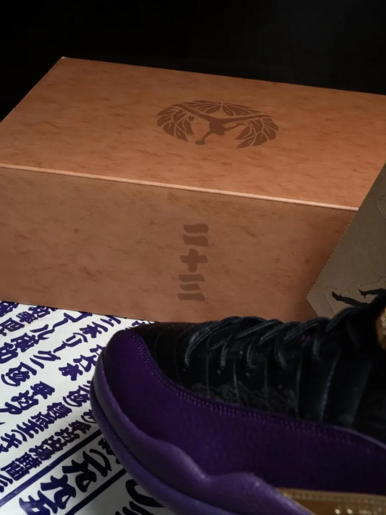 Brown Air Jordan Show Box With Laurel Jumpman Brand Beside A Black And Purple Air Jordan 12 And Japanese-Inspire Printed Paper