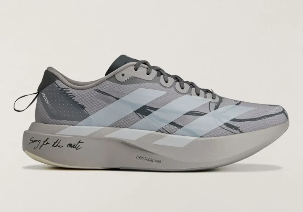 Side profile of a gray adidas Adizero shoe featuring pale stripes, a thick Lightstrike Pro midsole, and “Song for the Mute” script
