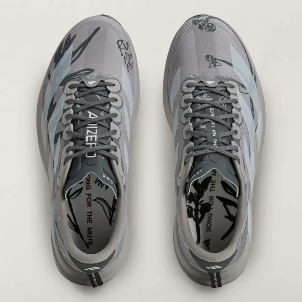 Top view of the pair showing gray laces, illustrated uppers, branded insoles, and “Song for the Mute” detail