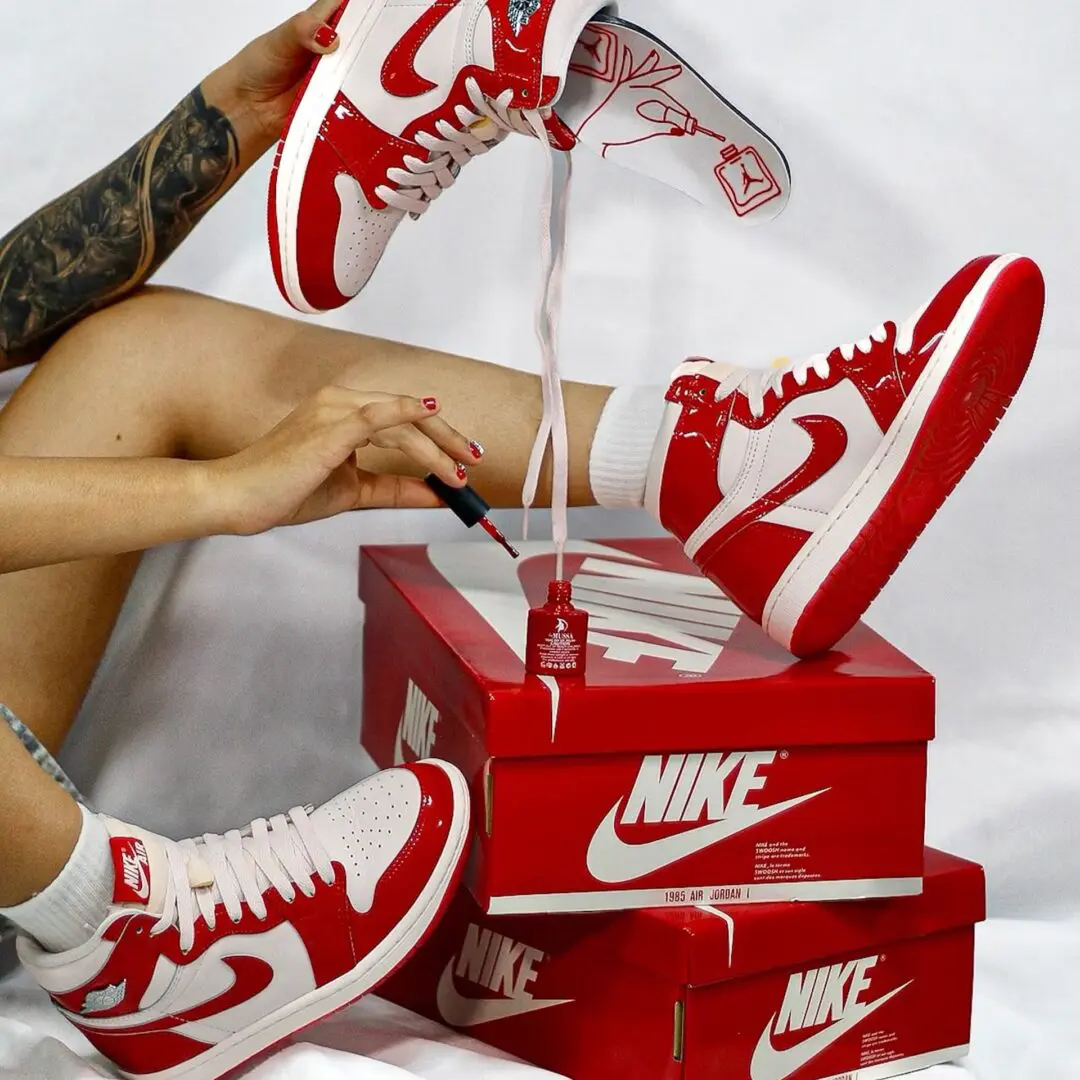 Person Applies Red Nail Polish Beside Air Jordan 1 Shoes And Nike Boxes