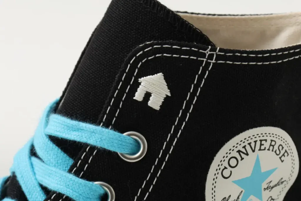 Close-up show blue lace, white stitch, a house emblem, and a blue-accent Converse ankle patch