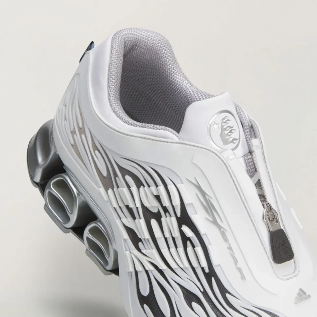 Close-up of the white upper featuring black flame graphics, gray mesh lining, zipper closure, and metallic heel cushion