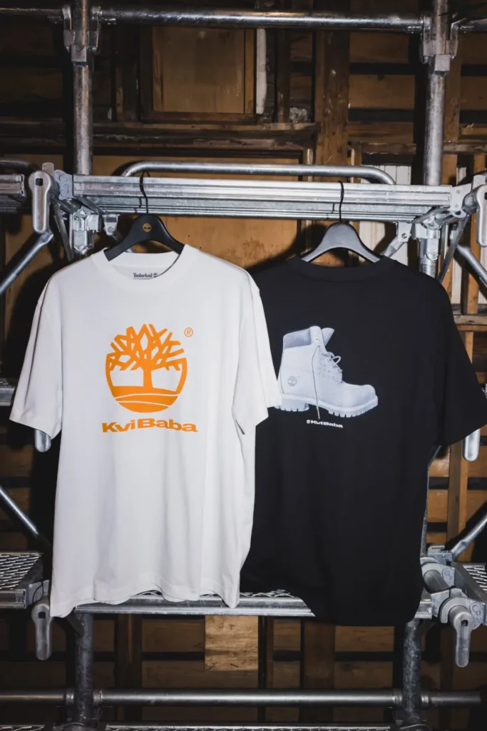 White and black Timberland x Kvi Baba graphic Tee hang from metal scaffold
