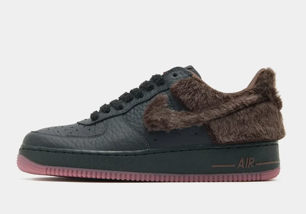Dark gray leather shoe with brown fur panel, black lace, “AIR” brand, and a translucent pink sole on a white