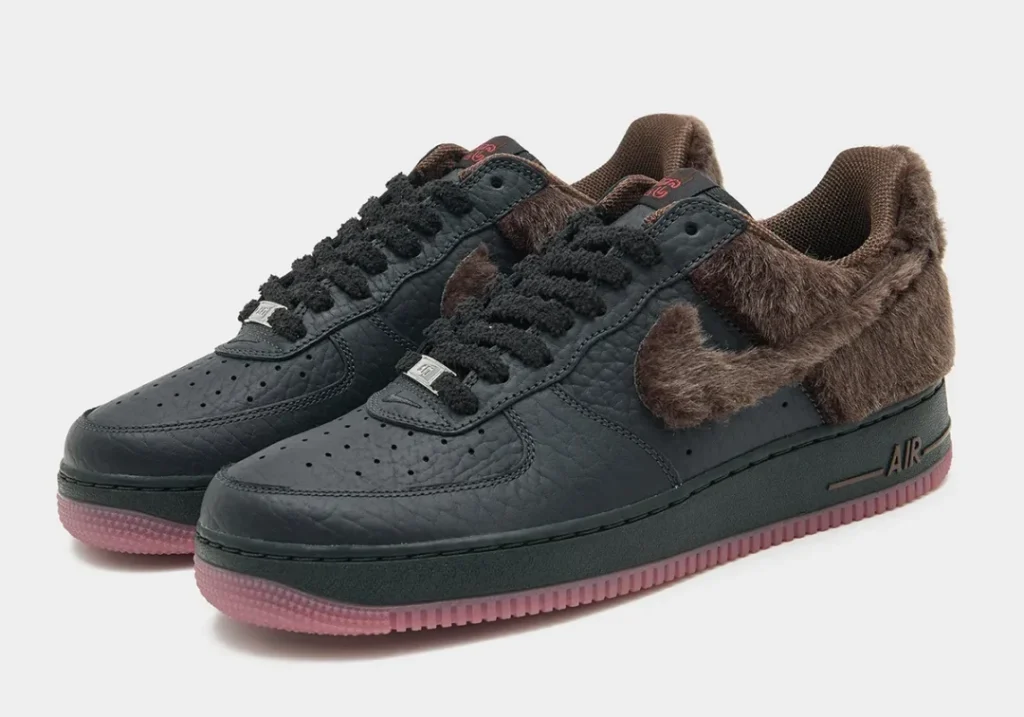 Pair of black leather shoe with brown faux-fur collar and swoosh, pink translucent sole, on a white background