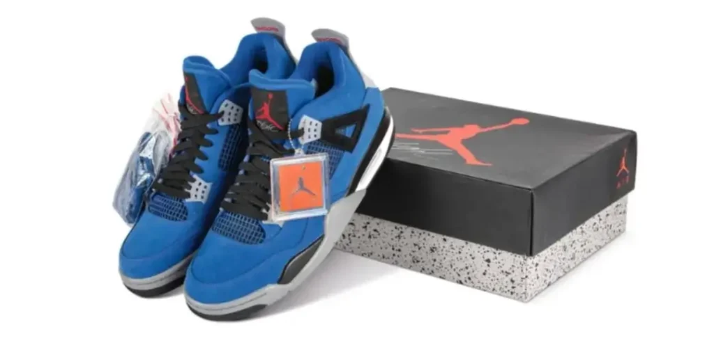 Pair of bright blue Air Jordan 4 shoe with black laces, gray accents, red Jumpman branding, attached tags, and a black-and-gray Jordan shoebox