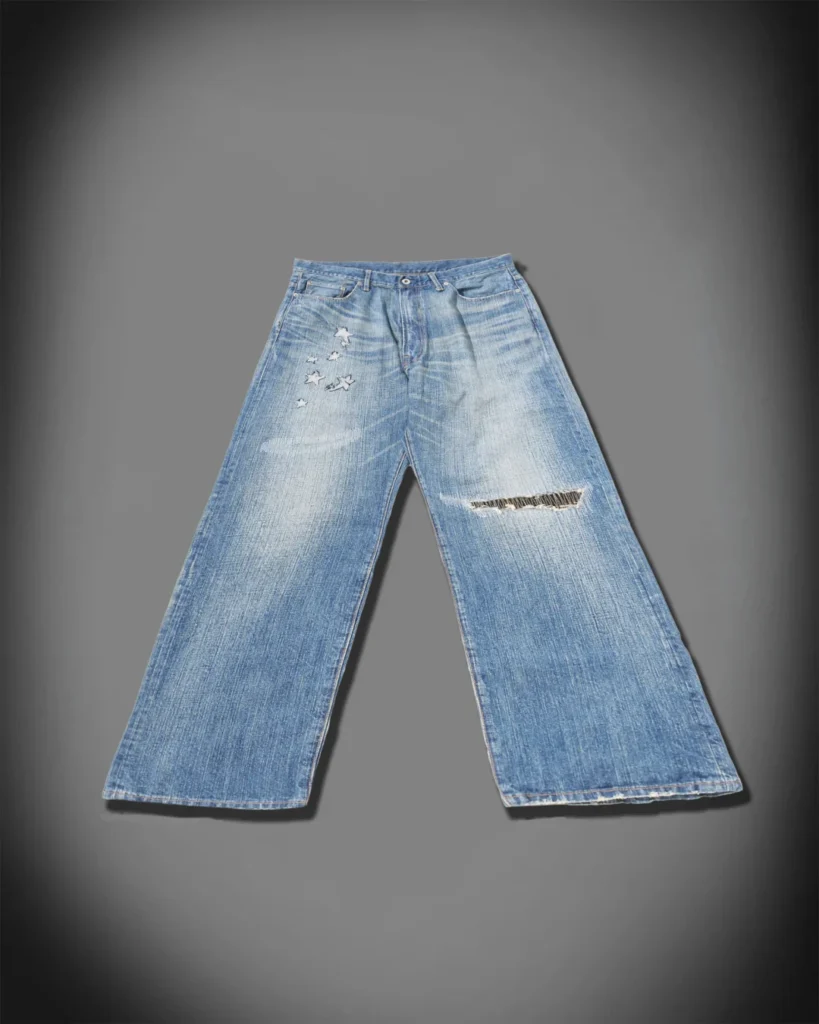 Front product view of fadedwide-leg blue jeans with star appliqués and a distress horizontal rip across one leg