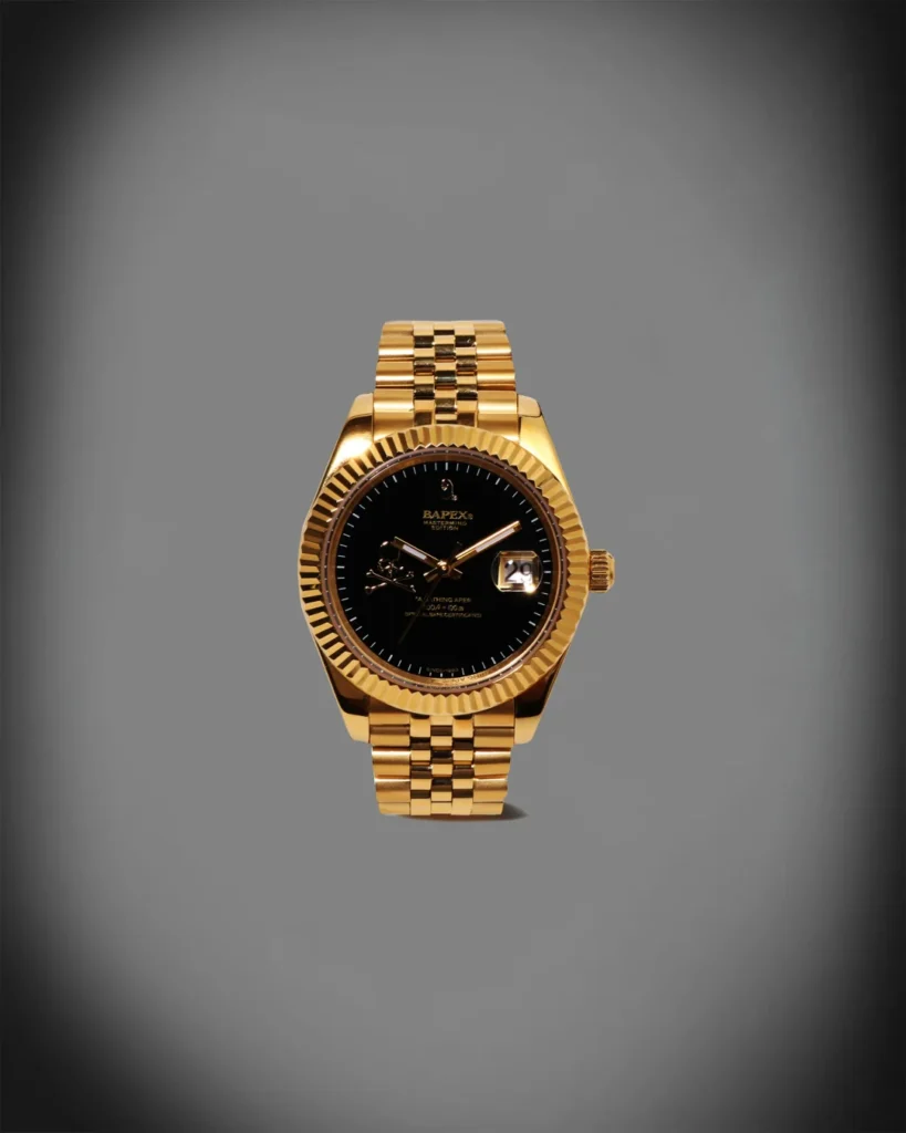 Gold-tone BAPEX wristwatch with black dial, flute bezel, date window and metal bracelet display against gray
