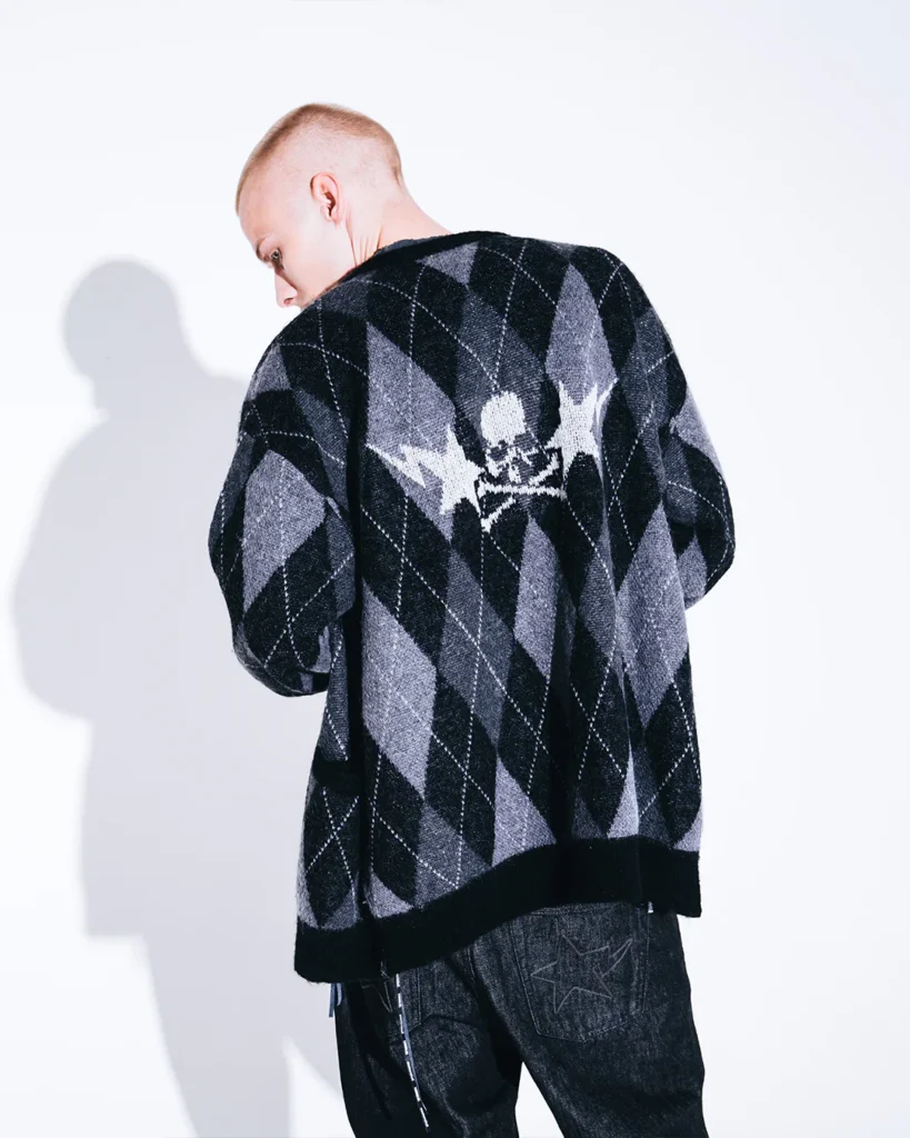 Rear view of the black-and-gray argyle cardigan featuring a knitted skull-and-crossbones graphic across the upper back