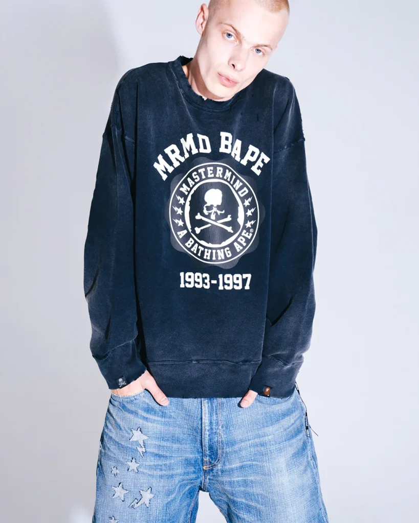 Model wear a wash black Mastermind x BAPE sweatshirt with skull-and-crossbones emblem and “1993–1997” letter, pair with faded jean