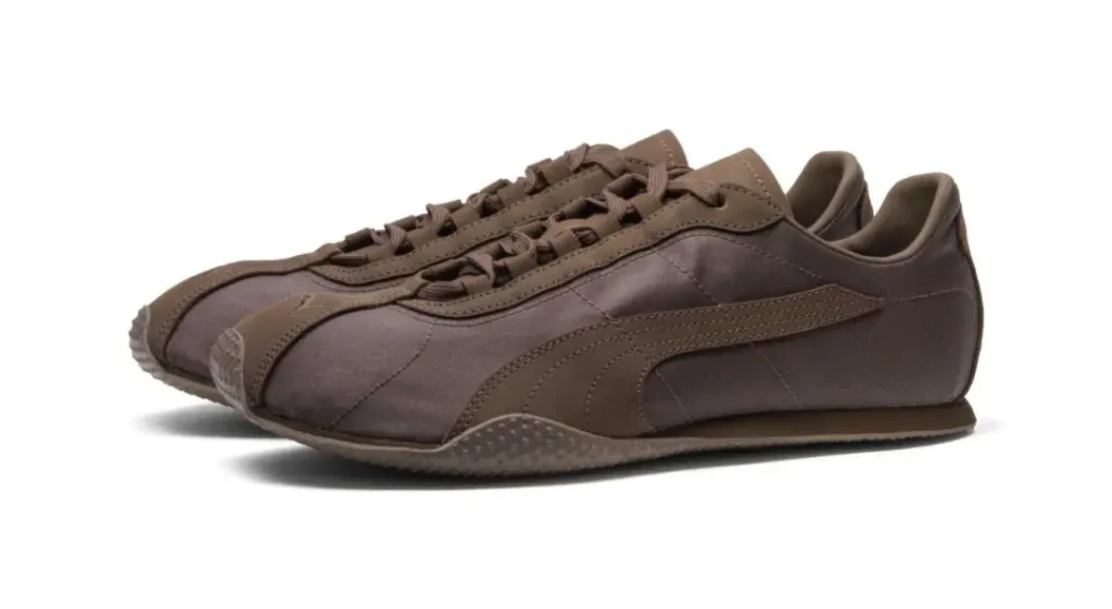 Pair of dark brown low-top sneakers with laces, curved side stripes, and textured rubber soles on a white background