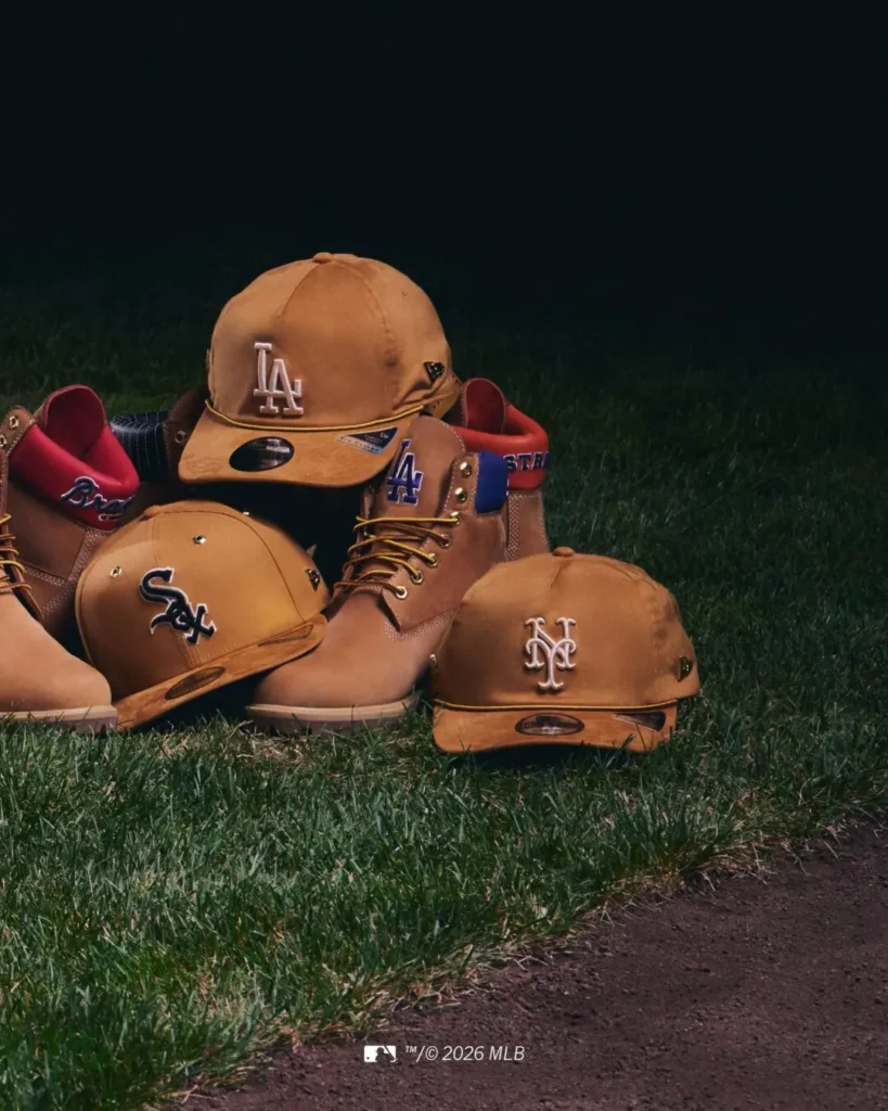 Tan work boots and matching fitted MLB caps representing multiple teams arranged across a dark baseball field