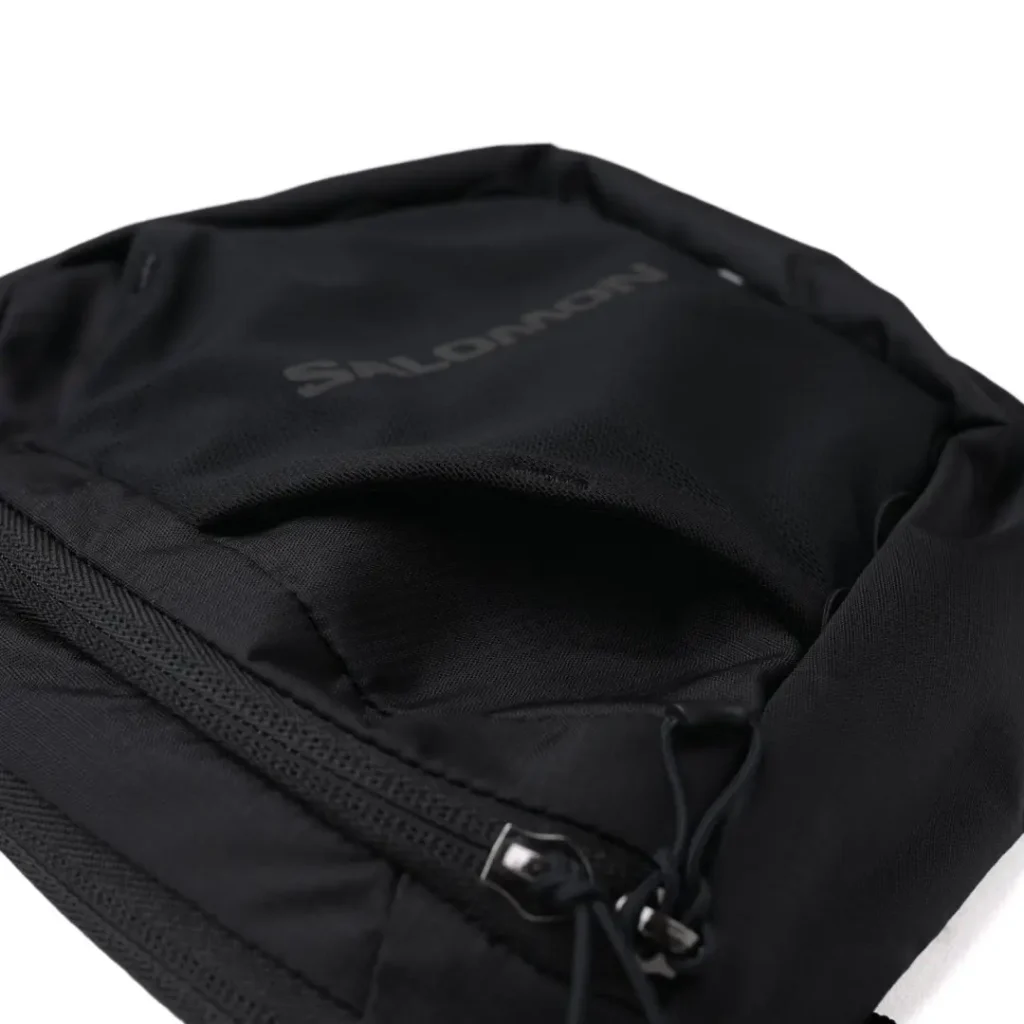 Close-up of the front stretch mesh pocket with tonal Salomon branding, elastic construction, and ripstop trim for quick-access storage