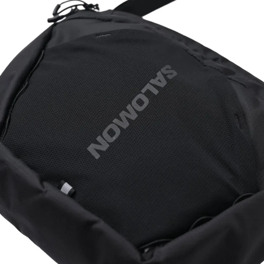 Close-up of the front mesh pocket featuring the tonal Salomon logo printed across the breathable fabric with subtle technical stitching and ripstop nylon trim