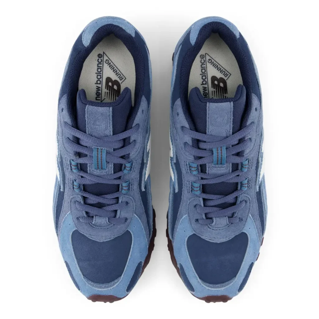 Top-down product view of a pair of blue New Balance shoes show tonal laces, layer suede upper and brand insole