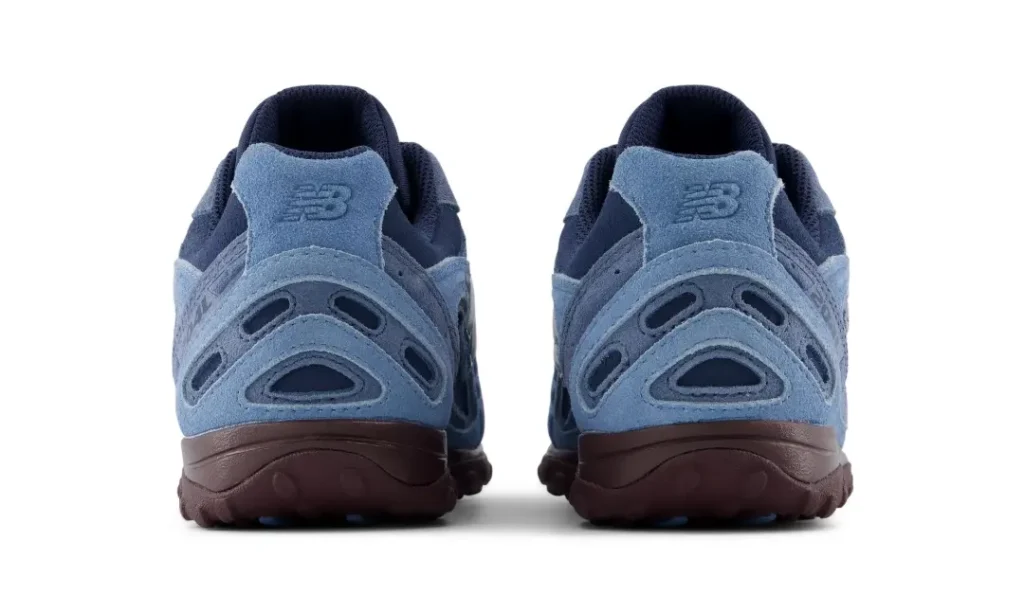 Rear product view of blue New Balance shoe on a white background, showing sculpt suede heel panel, NB brand and burgundy sole