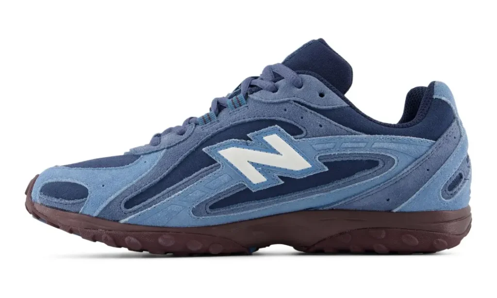 Opposite side profile of a blue New Balance shoe on a white background with layered blue suede construction and burgundy sole