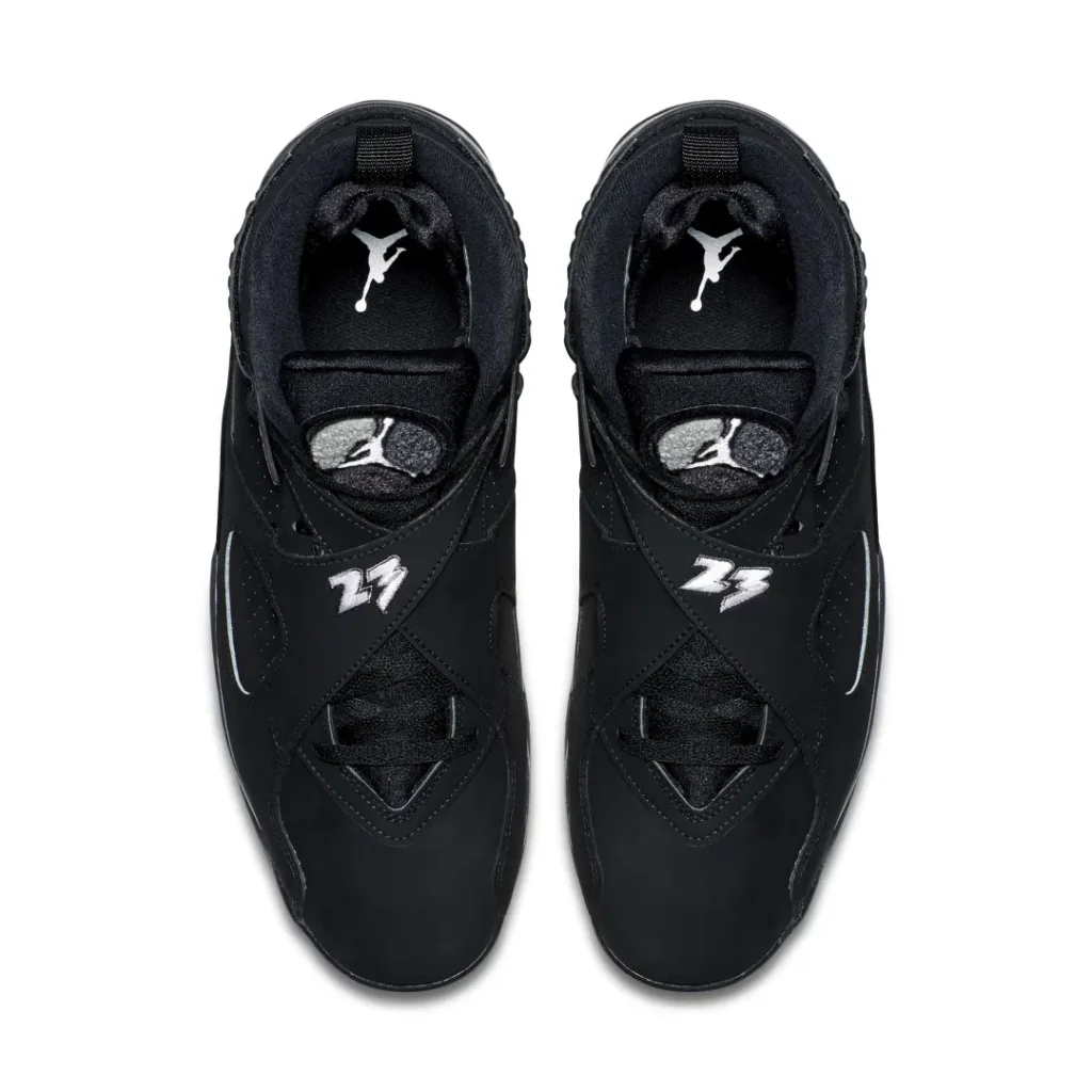 Top-down view of black Air Jordan 8 sneakers with cross straps, white logos, and visible tongue and insole details on white