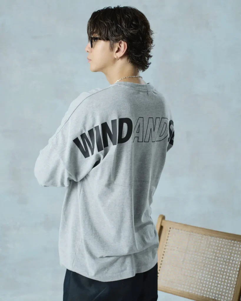 Rear three-quarter view of the gray sweatshirt featuring oversized "WIND AND SEA" graphics across the back