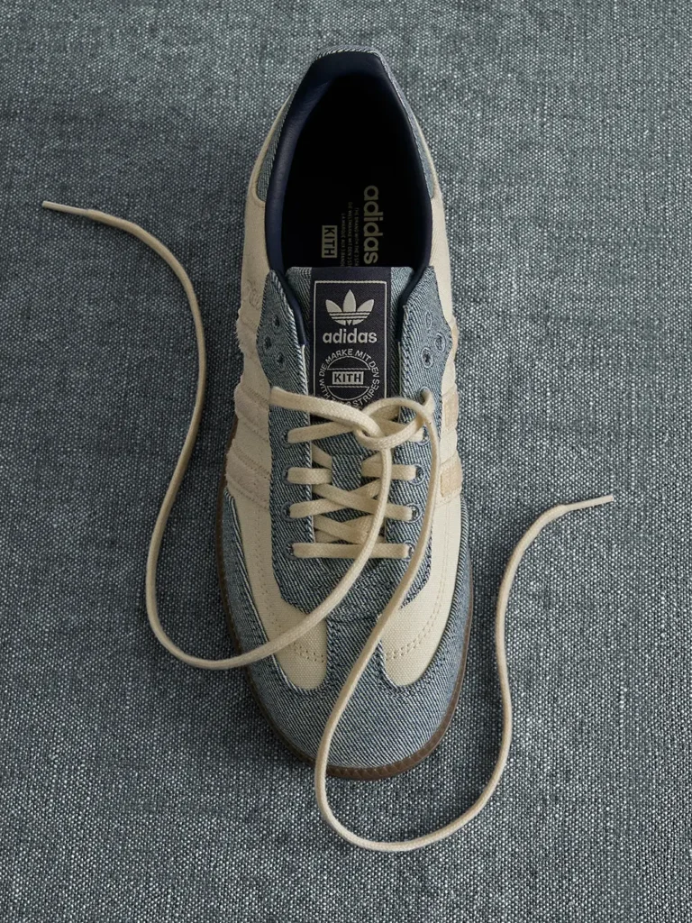 Top-down view of a beige and gray Adidas sneaker with loose laces on textured gray fabric