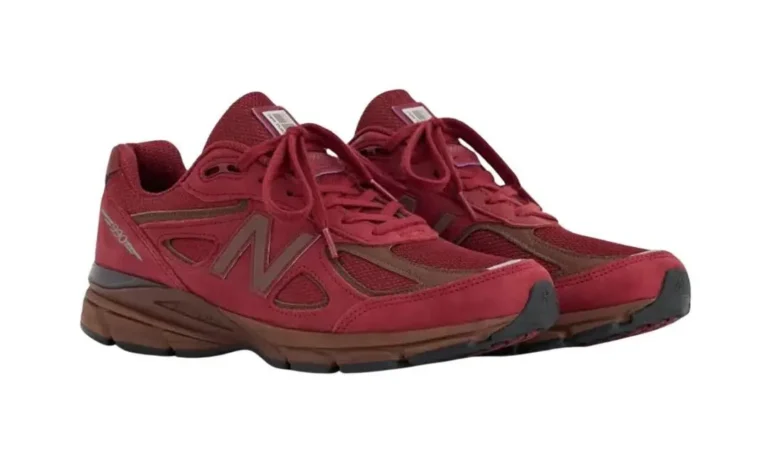 Pair of burgundy New Balance 990 shoe on a white background, shown from a three-quarter front angle. Both shoe have a suede and mesh upper in deep maroon, a large grey “N” logo on the side, burgundy lace, a brown midsole, and a dark outsole