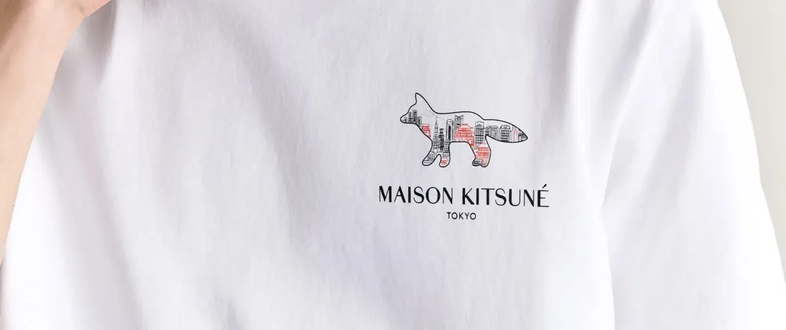 Close-up of a white Maison Kitsuné Tokyo T-shirt showcasing the fox cityscape graphic and logo printed on the left chest.