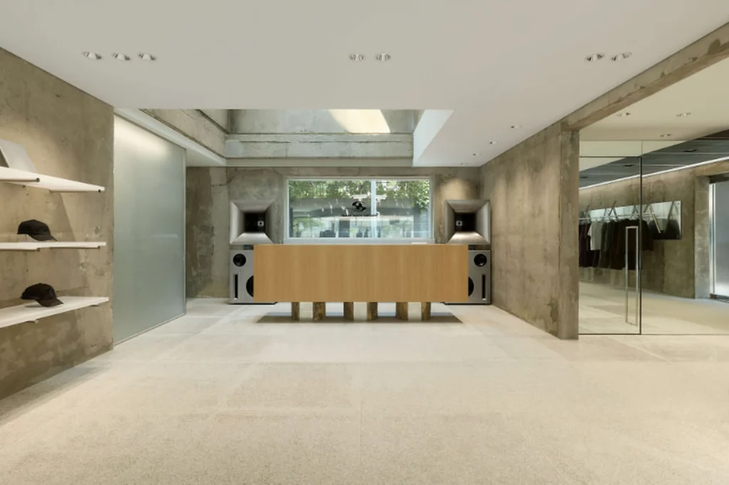 Concrete Fashion Store Interior With Wooden Counter And Integrated Speaker