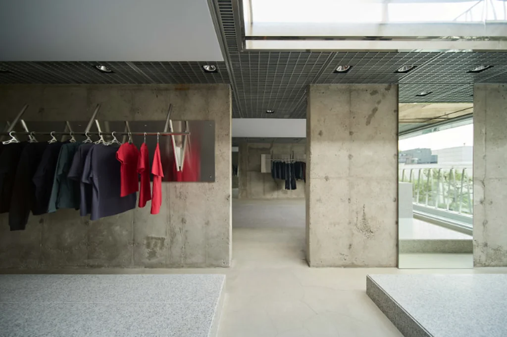 Concrete Retail Interior With Red And Dark Clothing Hanging On Metal Rail