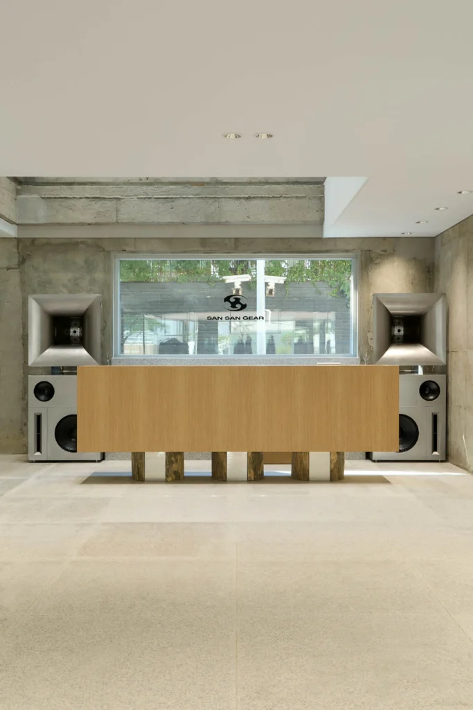 Wooden Counter And Large Speakers Inside Raw Concrete Fashion Store