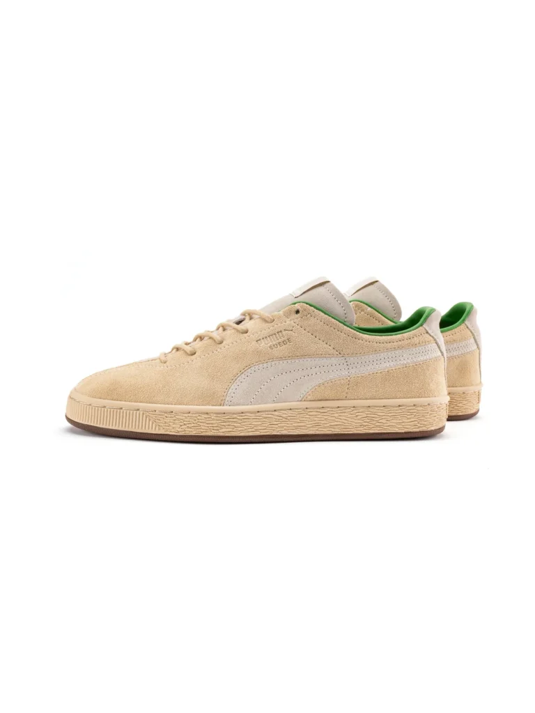 A side-profile view of the PUMA x le PÈRE Suede "Gentle Man" shoe in a beige "Cashew Brown" colorway. The premium suede upper features a view split-toe design near the front and a silver-grey PUMA Formstrip. The word "SUEDE" is emboss on the side, and a vibrant green inner line is view at the ankle. The shoe sits on a classic gum rubber sole with a texture midsole and a dark brown outsole