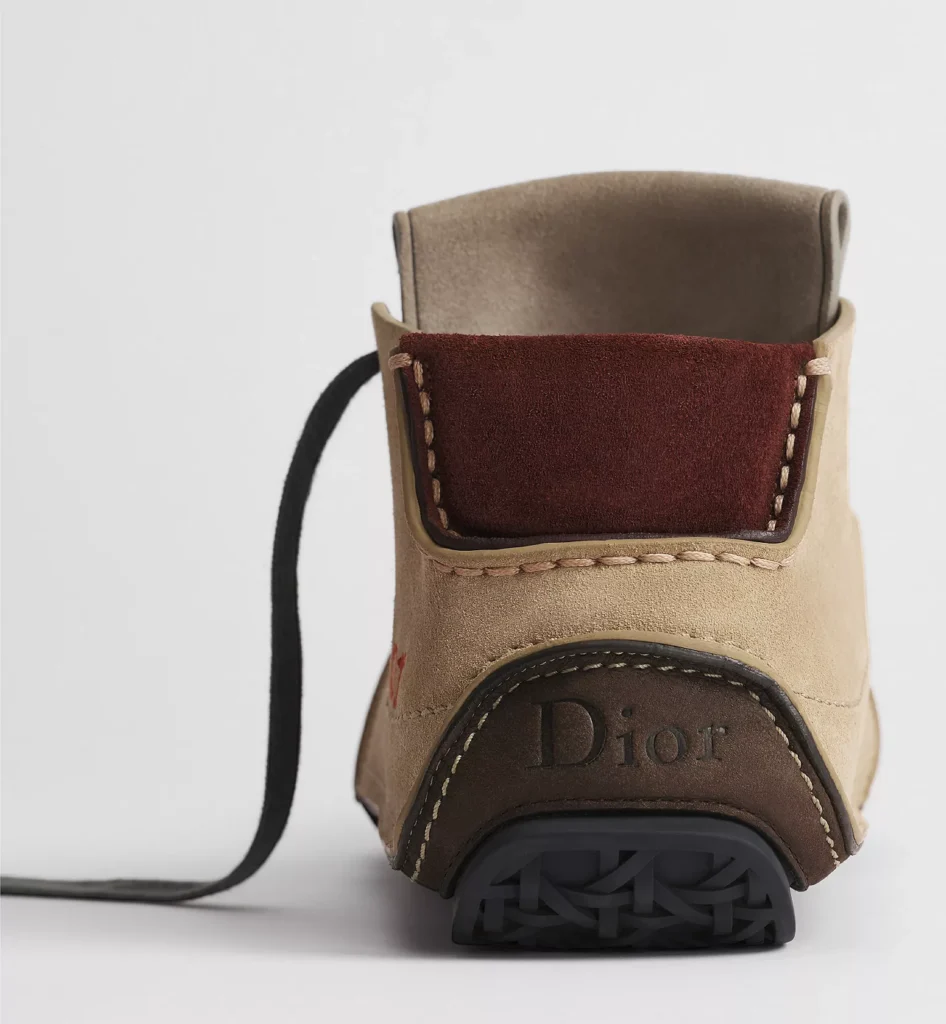 Rear view of a Dior high-top shoe showing layered suede panels, contrast stitching, burgundy heel tab, and black rubber sole
