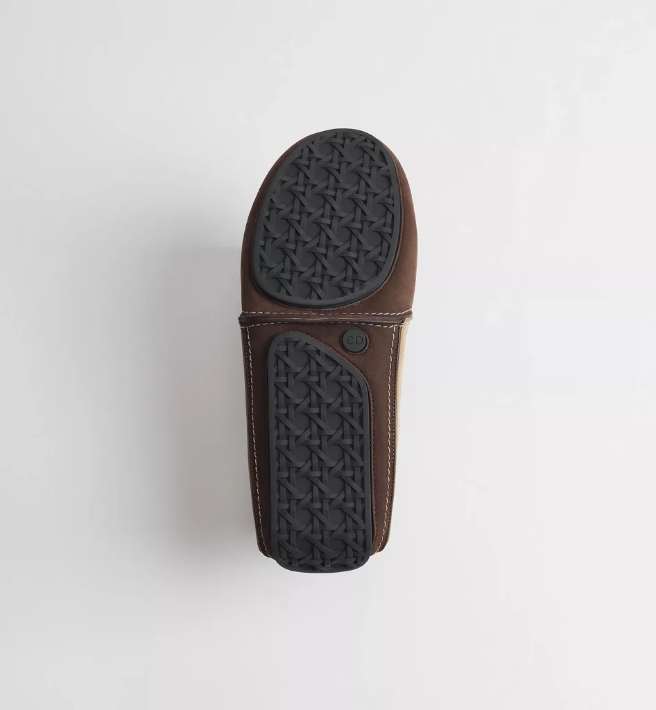Bottom view of a Dior shoe featuring a black textured rubber outsole with woven-pattern tread and CD detail