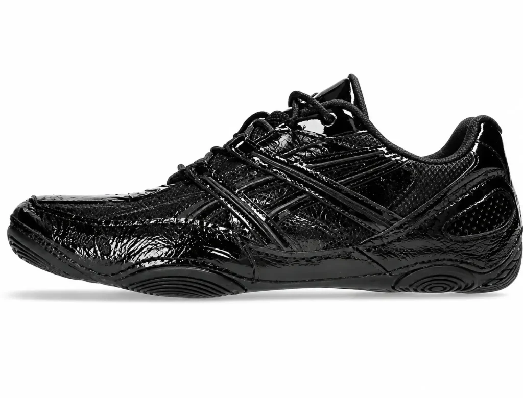 Side profile of a glossy black ASICS sneaker featuring a wrinkled patent leather upper, tonal ASICS stripes, and a low-profile sole