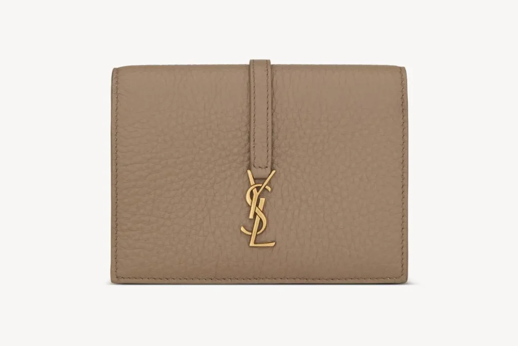Taupe grained leather bi-fold wallet secured by a vertical leather strap and finished with a gold-tone YSL monogram