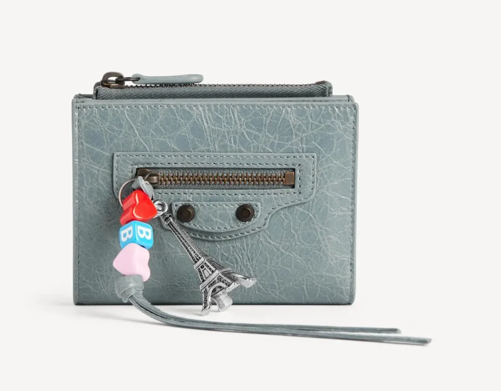 Distressed pale blue leather zip card holder with front zip pocket, wrist strap, and playful Eiffel Tower and colorful charm accessories
